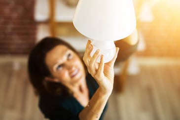 mujer colocando una ampolleta de eficiencia energética